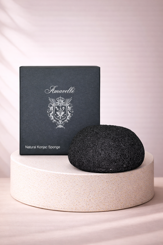 Black Konjac sponge on a white pedestal with Amavelle packaging in the background.