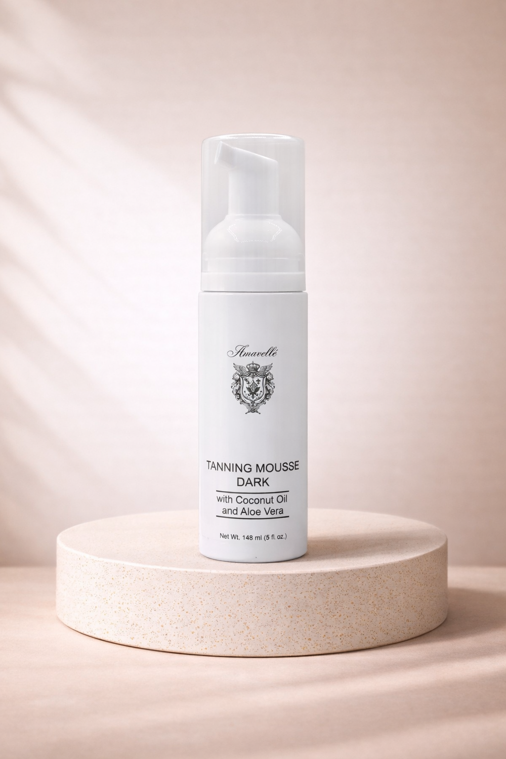 Tanning mousse bottle on a beige pedestal with a soft pink background